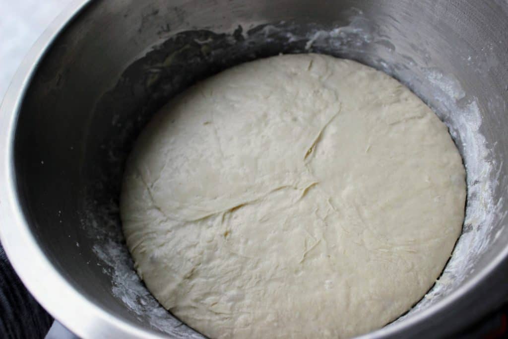 mixing bowl filled with risen pizza dough