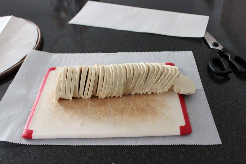 sugar cookie dough roll cut into slices on cutting board