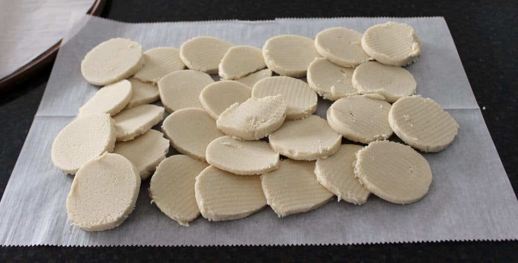 slices of sugar cookie dough spread out in a layer on parchment paper