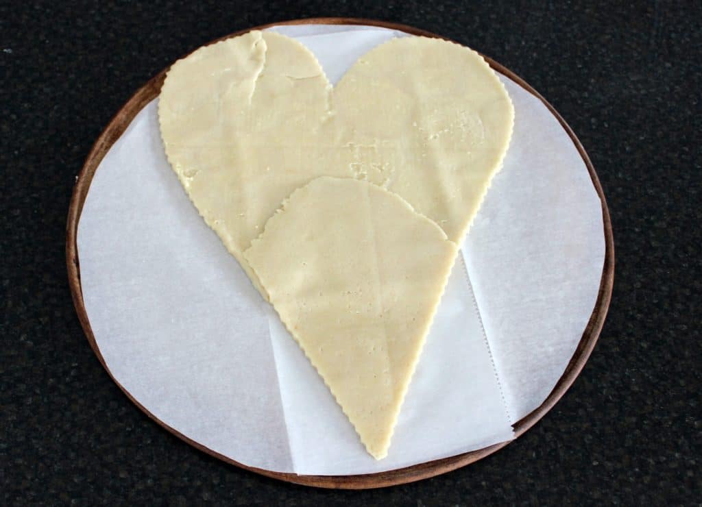 sugar cookie dough shaped into a large heart on round pizza stone
