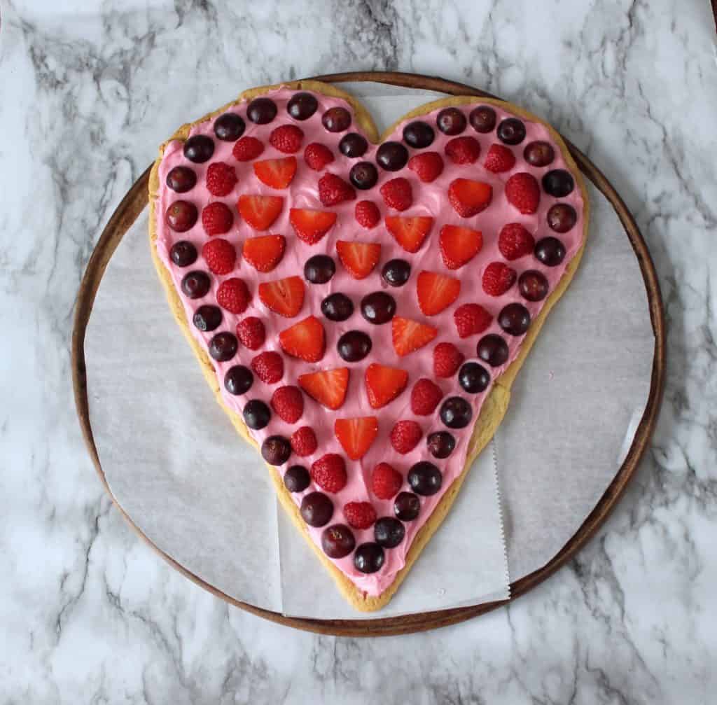 heart shaped fruit pizza on parchment lined pizza stone