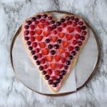 heart shaped fruit pizza on parchment lined pizza stone