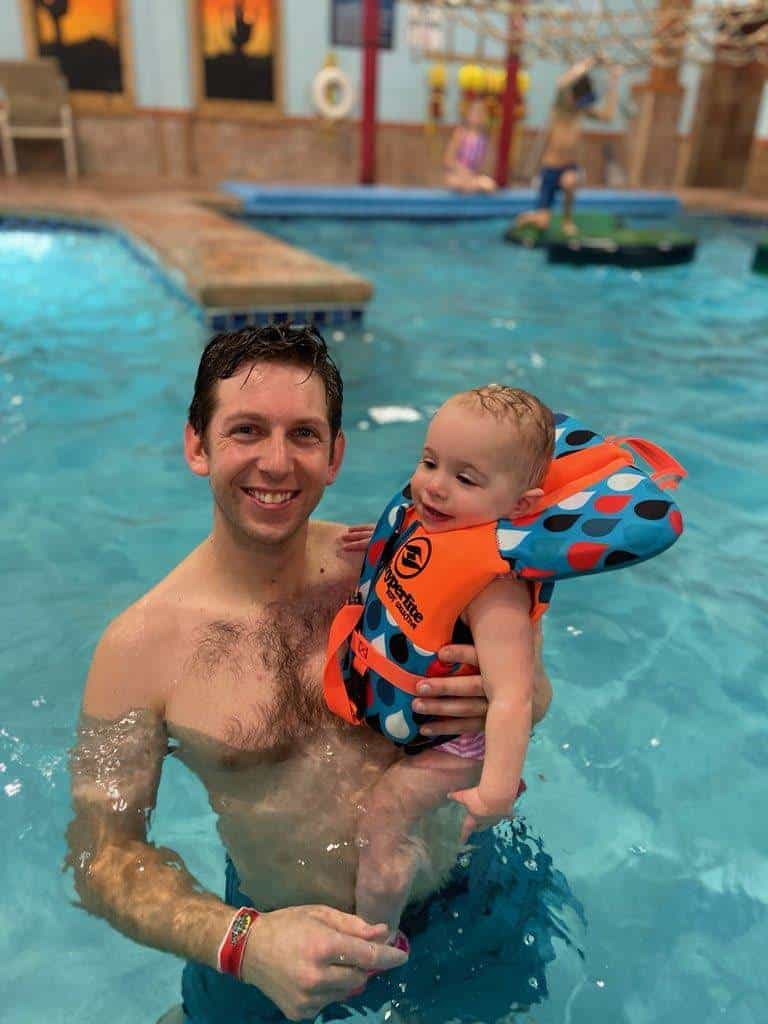 dad holding toddler in pool
