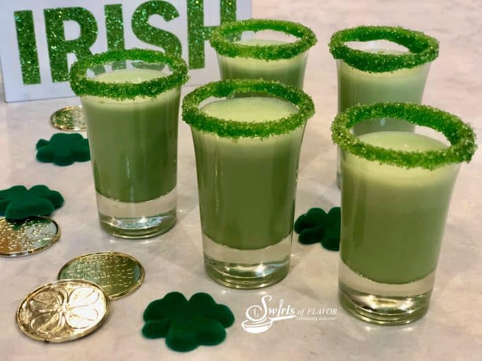 shot glasses filled with a green beverage rimmed in green sugar