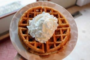 plate of waffles topped with whipped cream