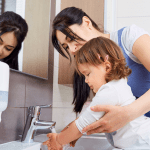 mom helping toddler wash hands