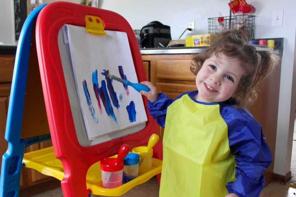 toddler girl painting at easel
