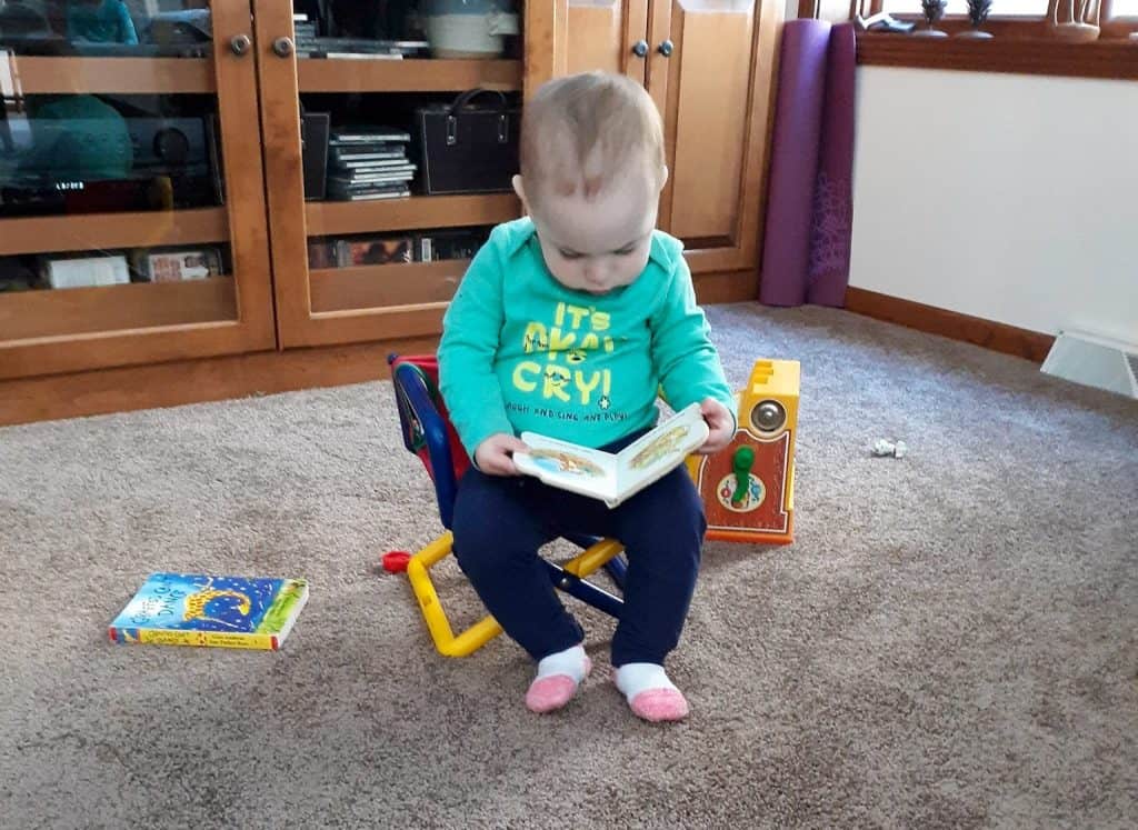 toddler sitting in chair reading