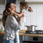 Smiling mom holding toddler in kitchen