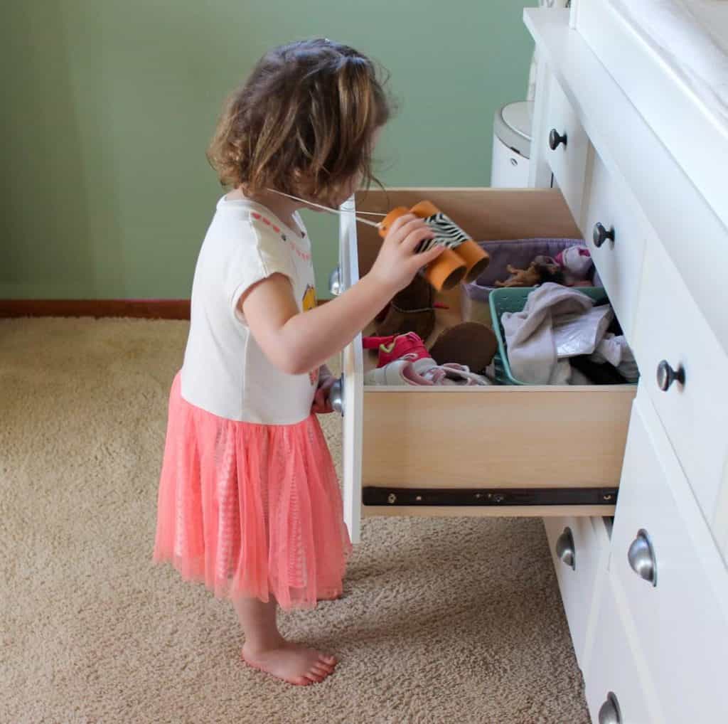 Toddler using her DIY binoculars looking in a sock drawer for a toy lion