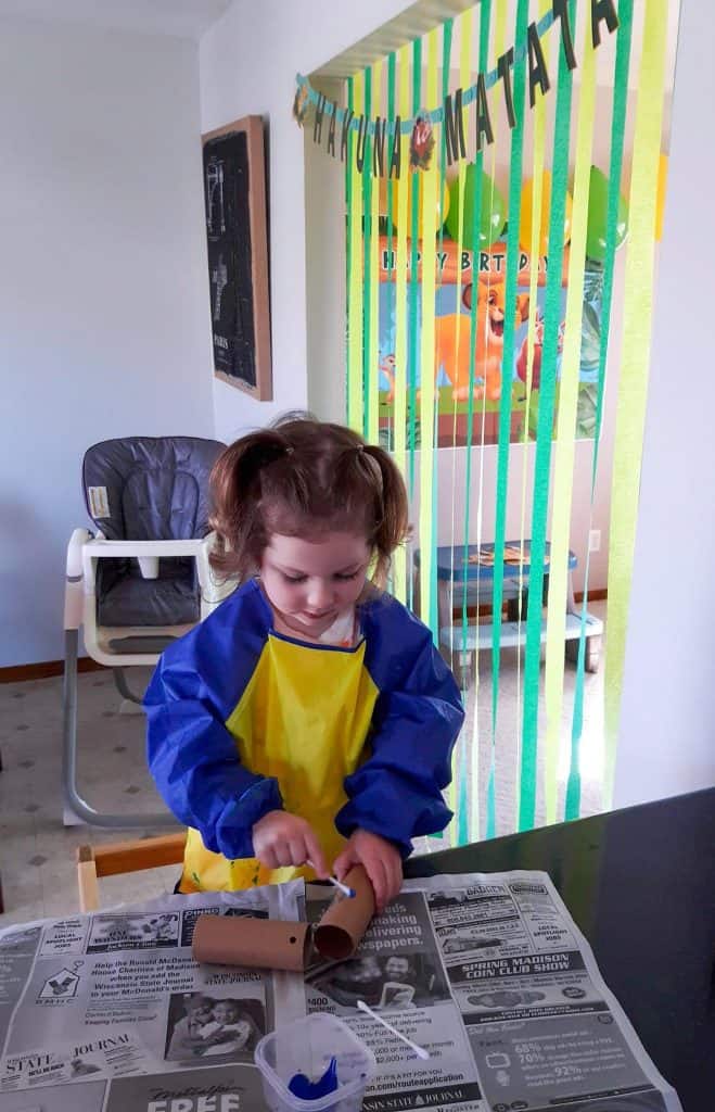 toddler wearing art smock painting a craft tube