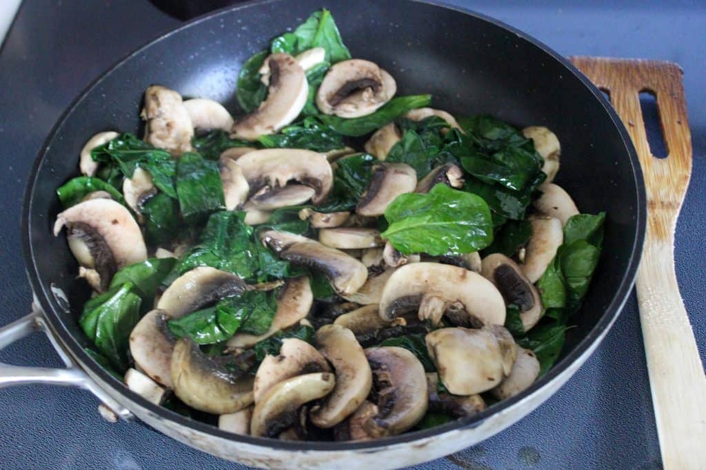 spinach and mushrooms in a frying pan