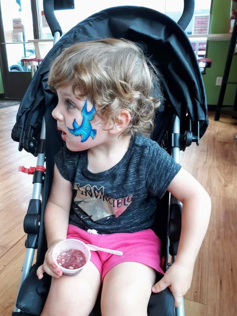 toddler with face paint sitting in stroller