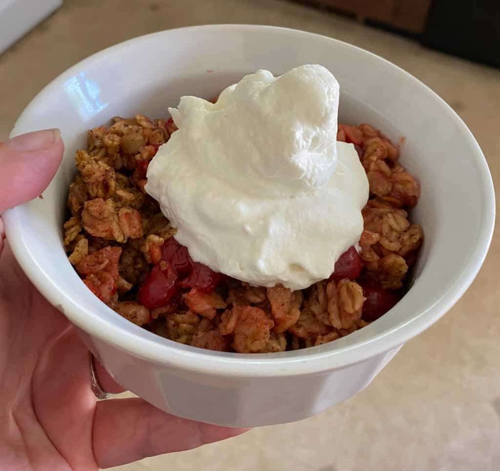 bowl of cherry pie oatmeal with whipped cream on top