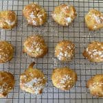 cream puffs sprinkled with powdered sugar on cooling rack