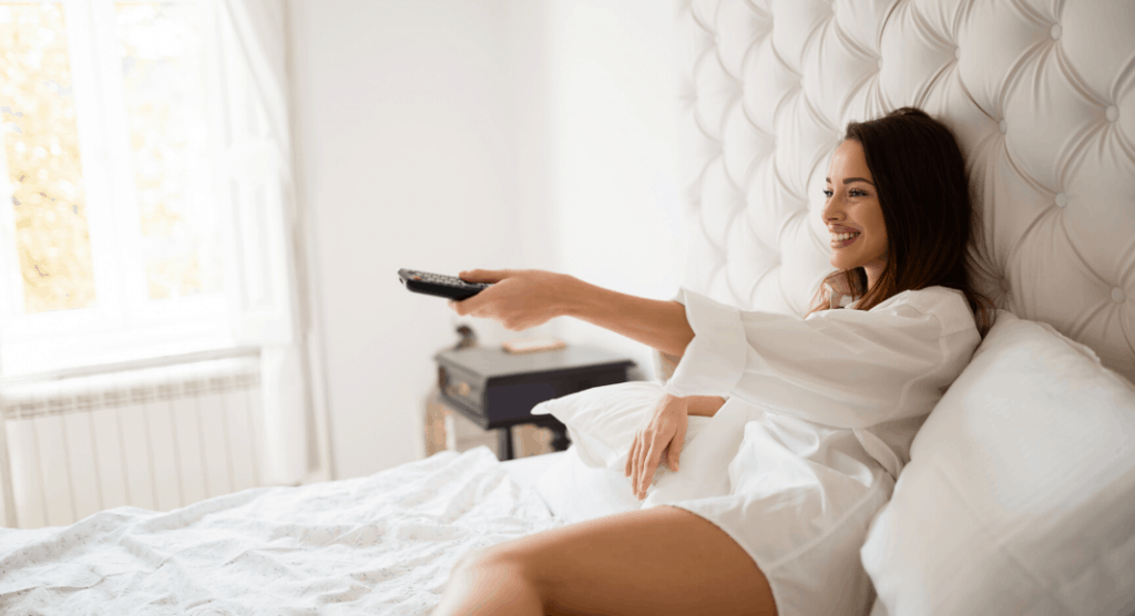 woman in bed holding remote