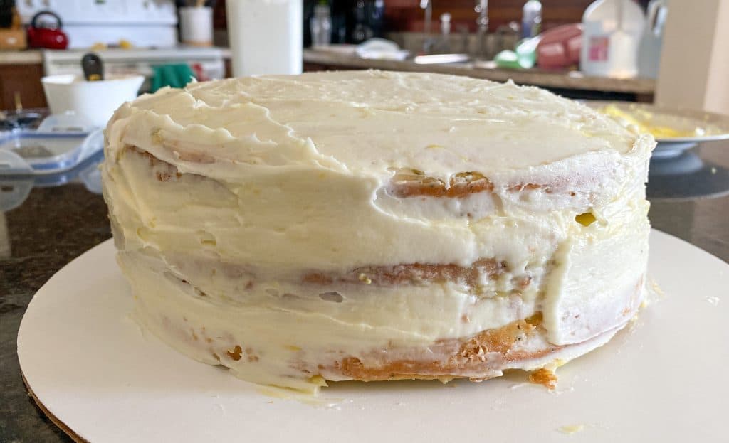crumb coat of frosting over layered cake
