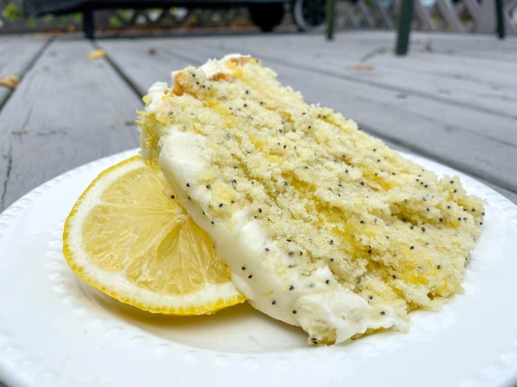 a slice of lemon poppy seed cake on a plate with a slice of lemon