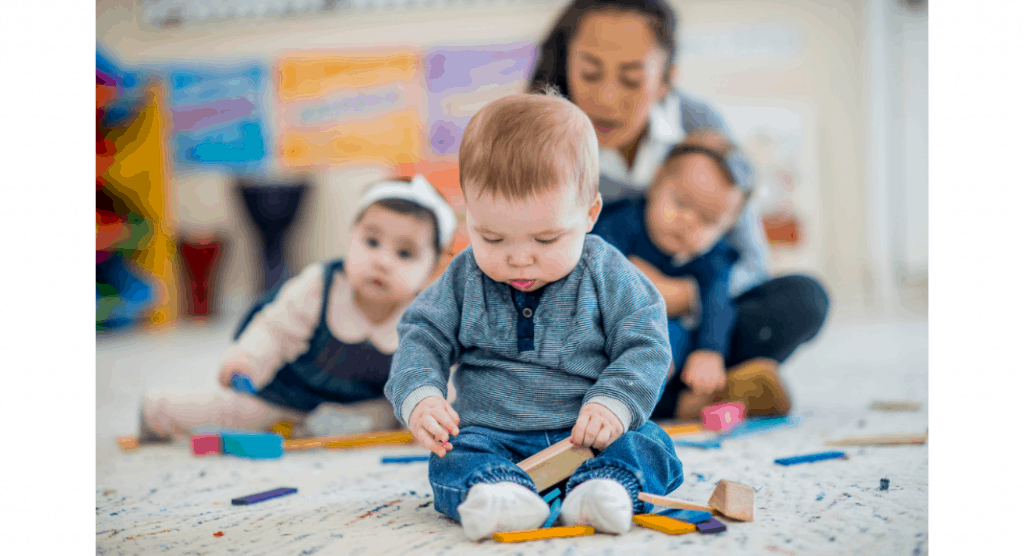 three babies sitting on floor with adult in background