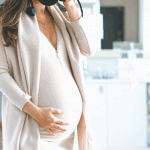 close up of woman's pregnant belly dressed for Fall