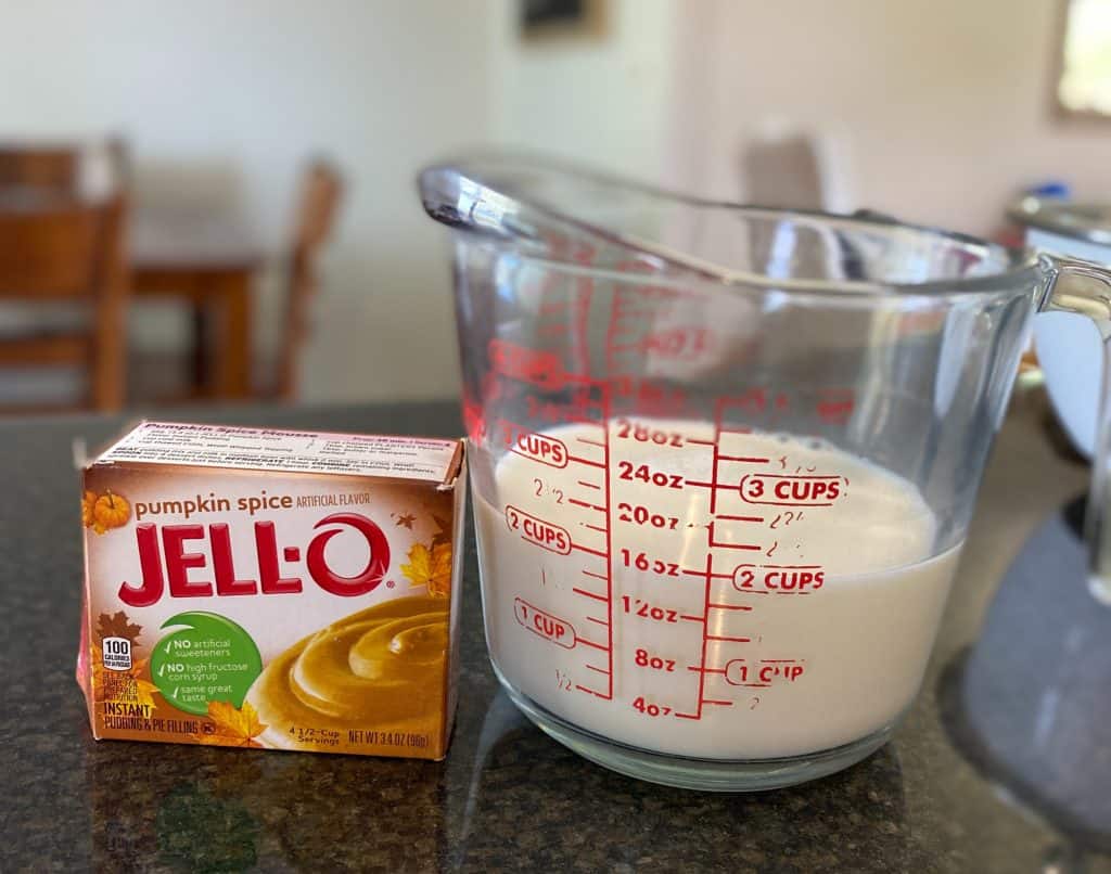 box of pumpkin spice instant pudding next to measuring cup filled with two cups of milk