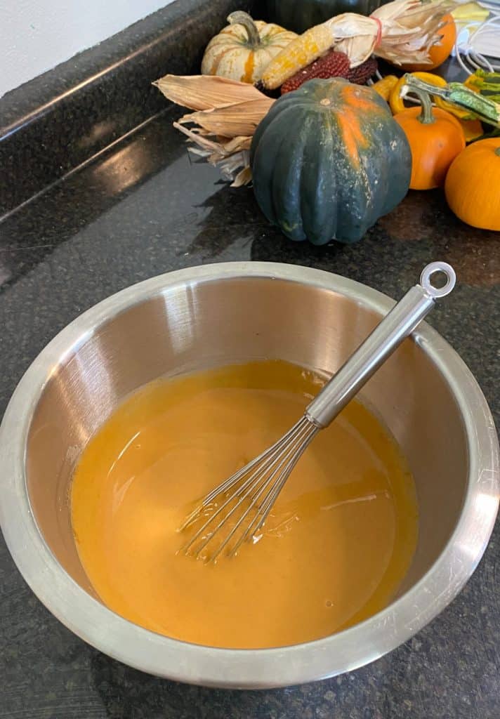 mixing bowl of pumpkin pudding with a whisk in it