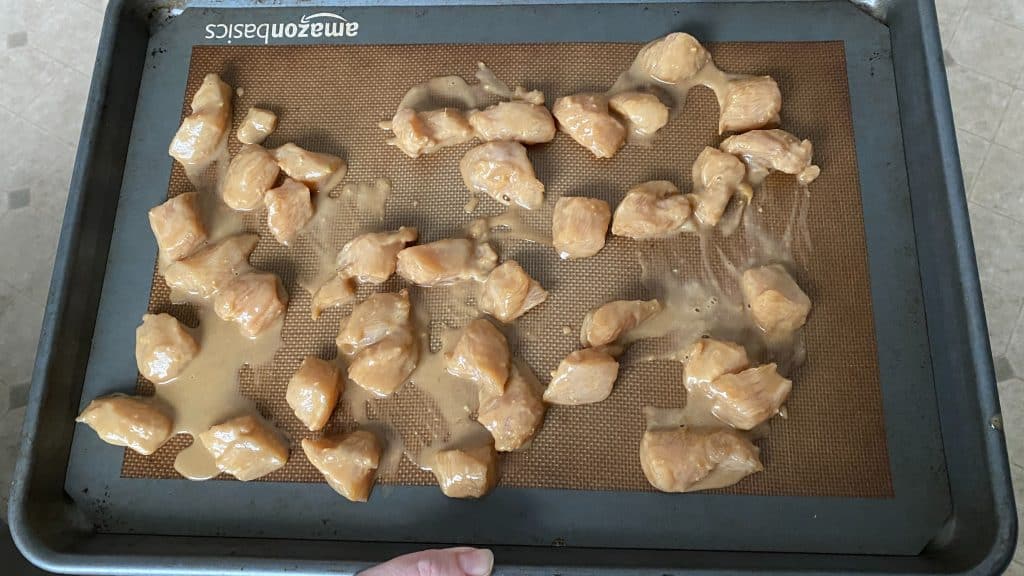 bite-sized marinated raw chicken on baking pan