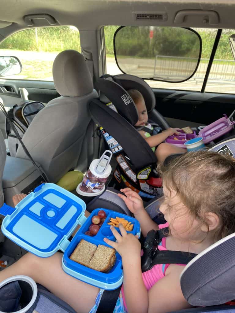 kids in car with lunch boxes on their laps