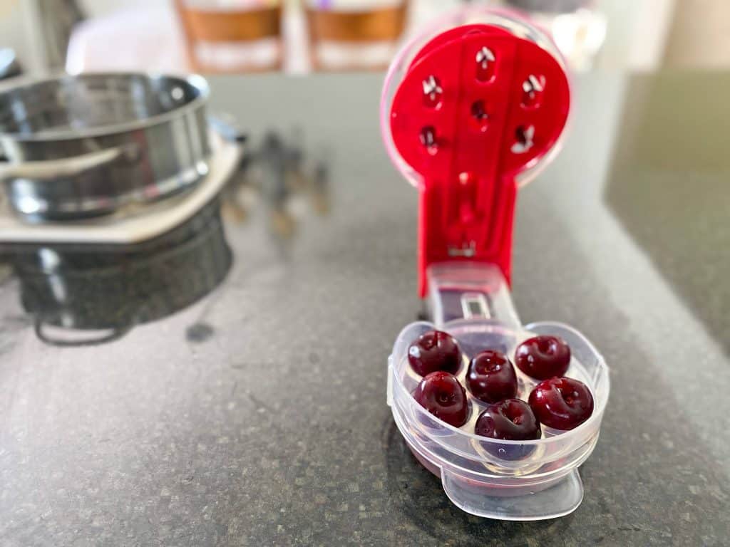 cherry pitter with six cherries sitting in it