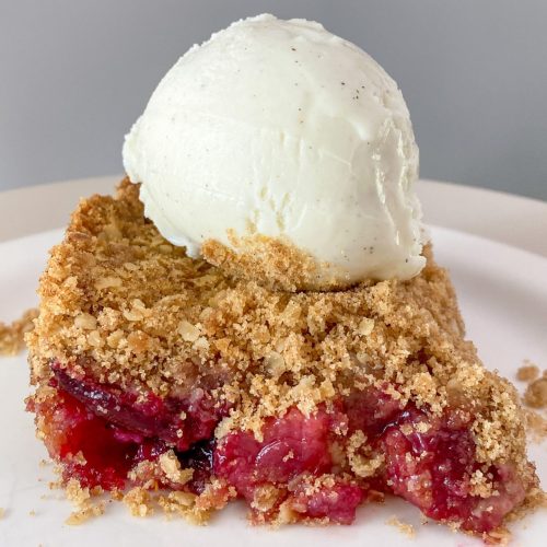 square of Cherry Berry Crisp with a scoop of vanilla ice cream on top