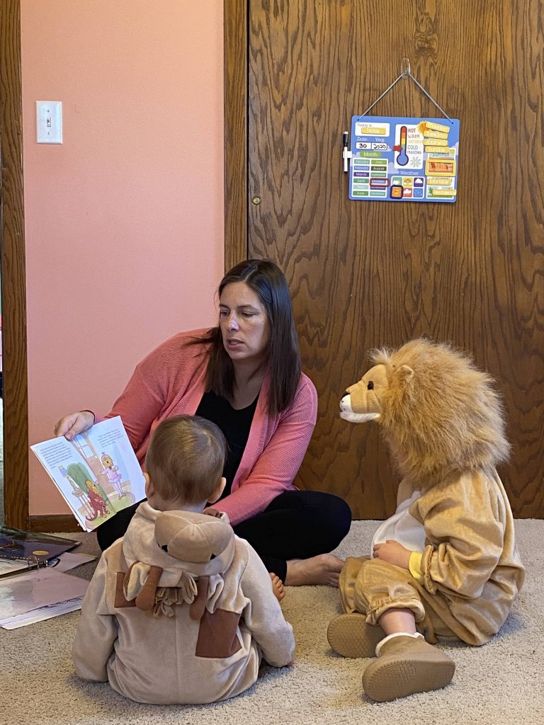 mom reading to two toddlers in Halloween costumes