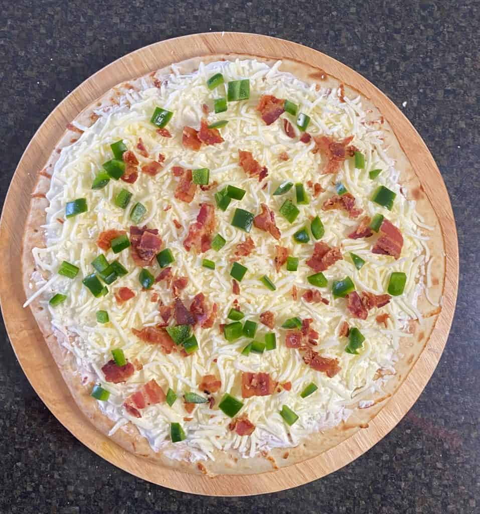 diced bacon pieces and jalapeno on top of the mozzarella cheese