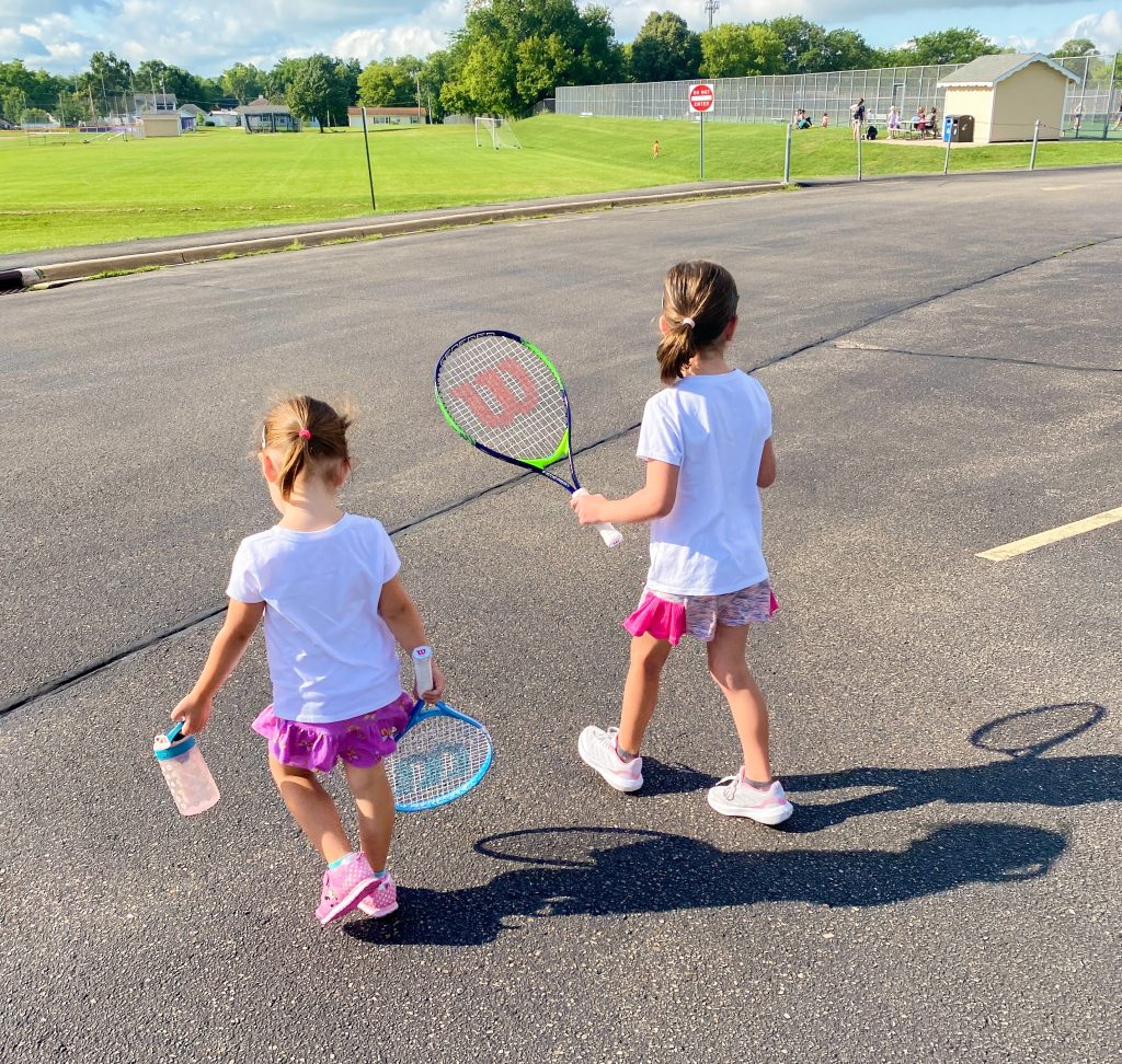two kids walking with tennis rackets