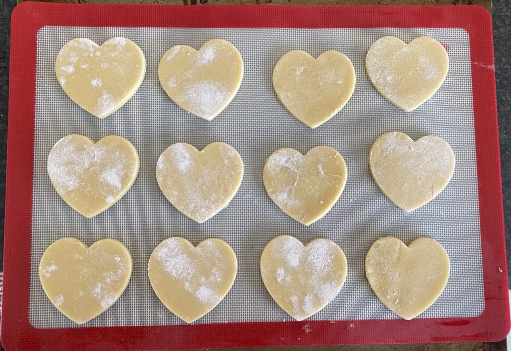 Sugar cookie heart shaped cut outs on silicone baking mat