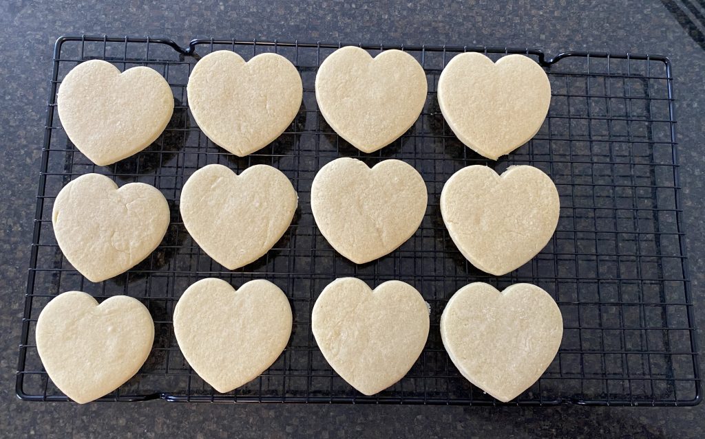 Baked heart shaped sugar cookies on cooling rack