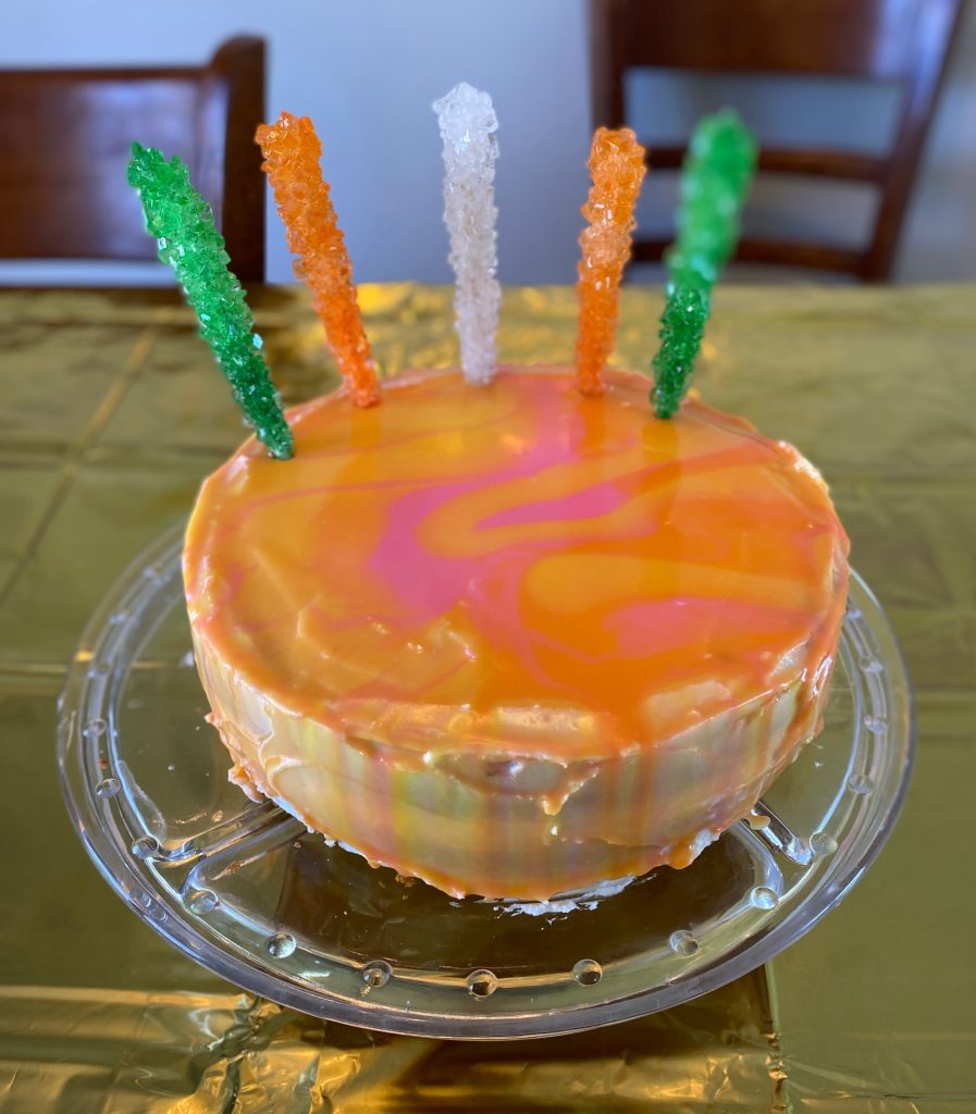 Completed birthday cake with mirror glaze and 5 rock candy sticks