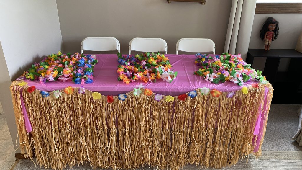 table with grass skirt and leis for guests on top