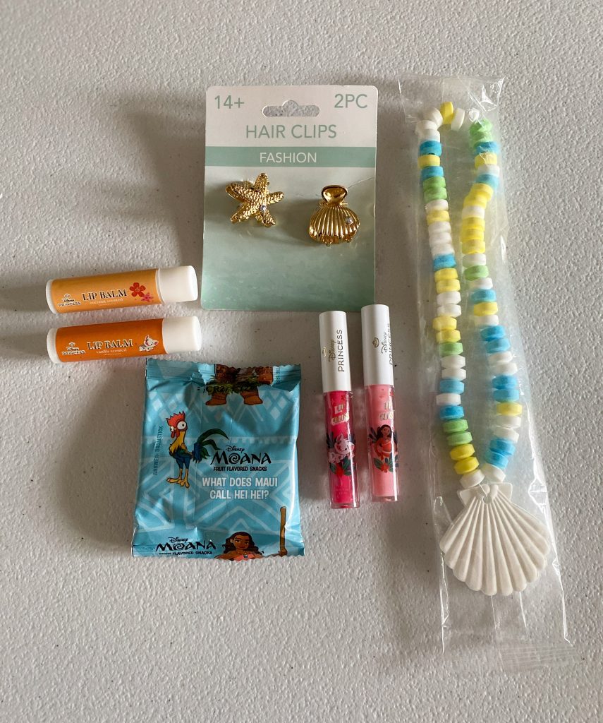 party favors: shell candy necklace, Moana lip gloss and Chapstick, Moana fruit snacks, and shell hair clips