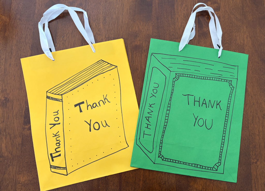 two favor bags with books drawn in Sharpie on the bags