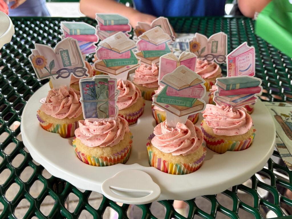 vanilla cupcakes with strawberry frosting and book-themed toppers